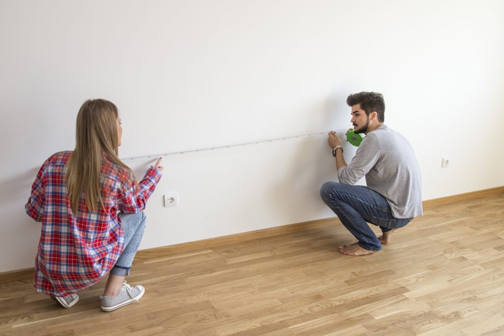 A couple is measuring a room.