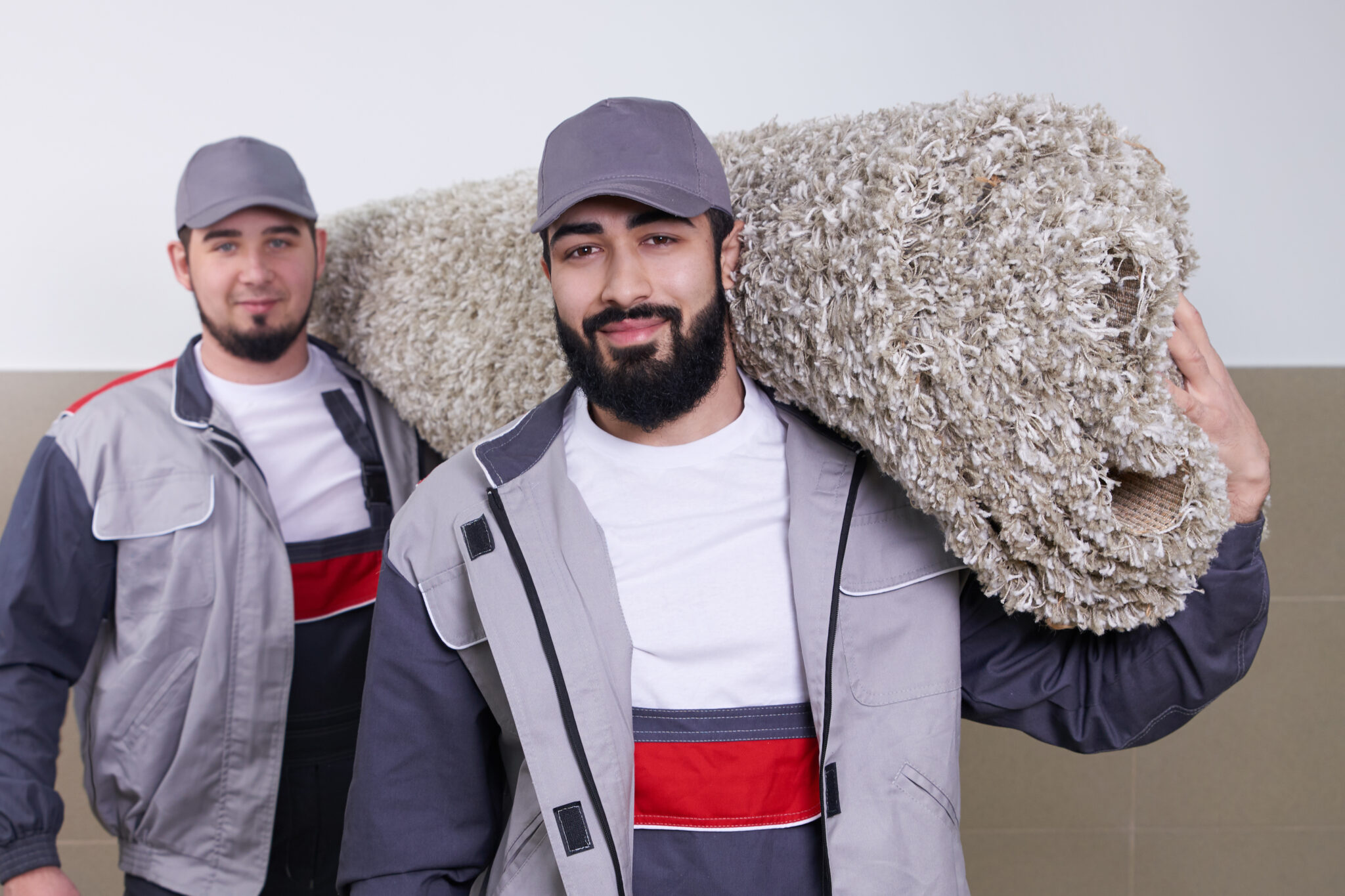 Two workers carrying big carpet roll The Carpet Guys