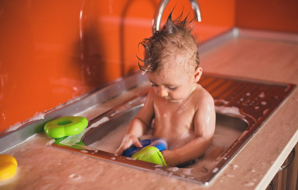 Cute Baby Boy taking a bath in Kitchen Sink